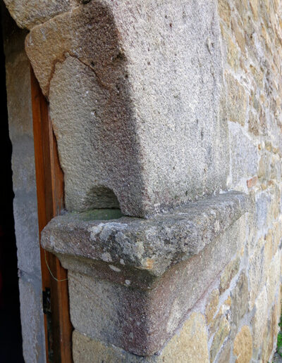 Un pequeño hueco tallado en el intradós de la puerta principal hace las veces de aguabenditera.