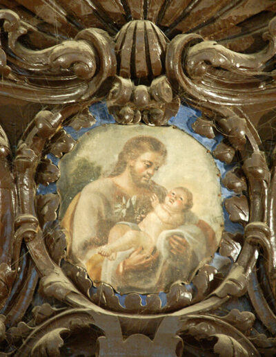 Medallón con la imagen de San José y el Niño que remata el retablo.