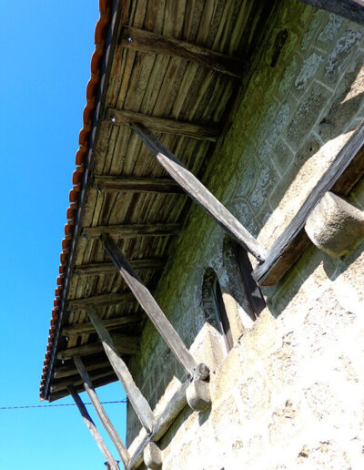 Al exterior, el alero del tejado apoya sobre tornapuntas con clavos de madera, que a su vez asientan en modillones de piedra.